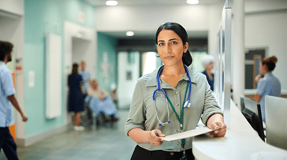 Female doctor leaning on the reception desk while holding a form.
