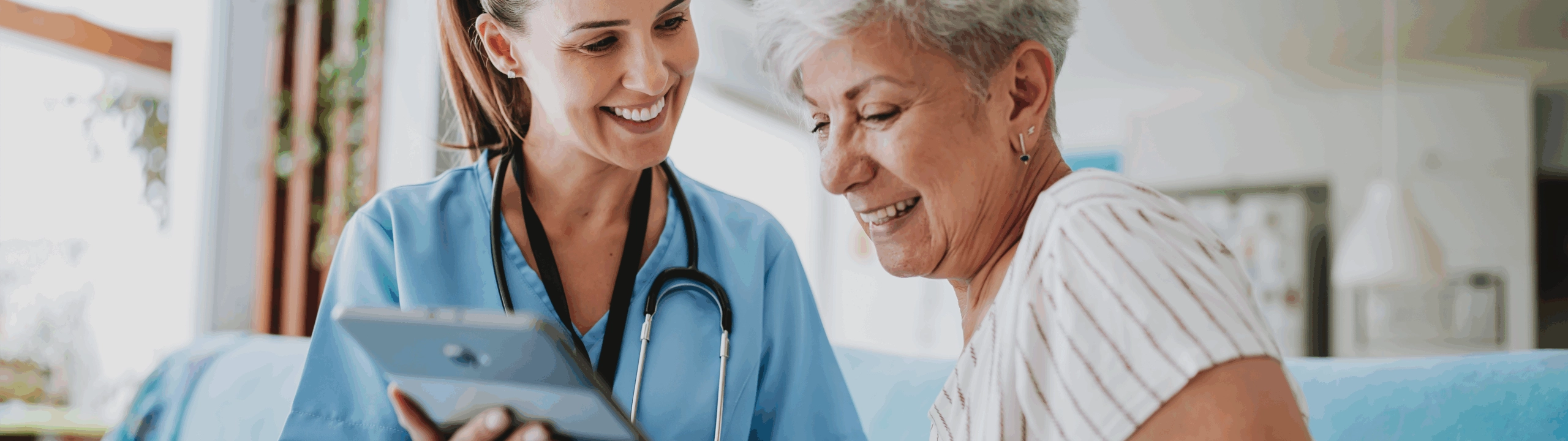 Happy elderly female reading the tablet her doctor is holding for her.