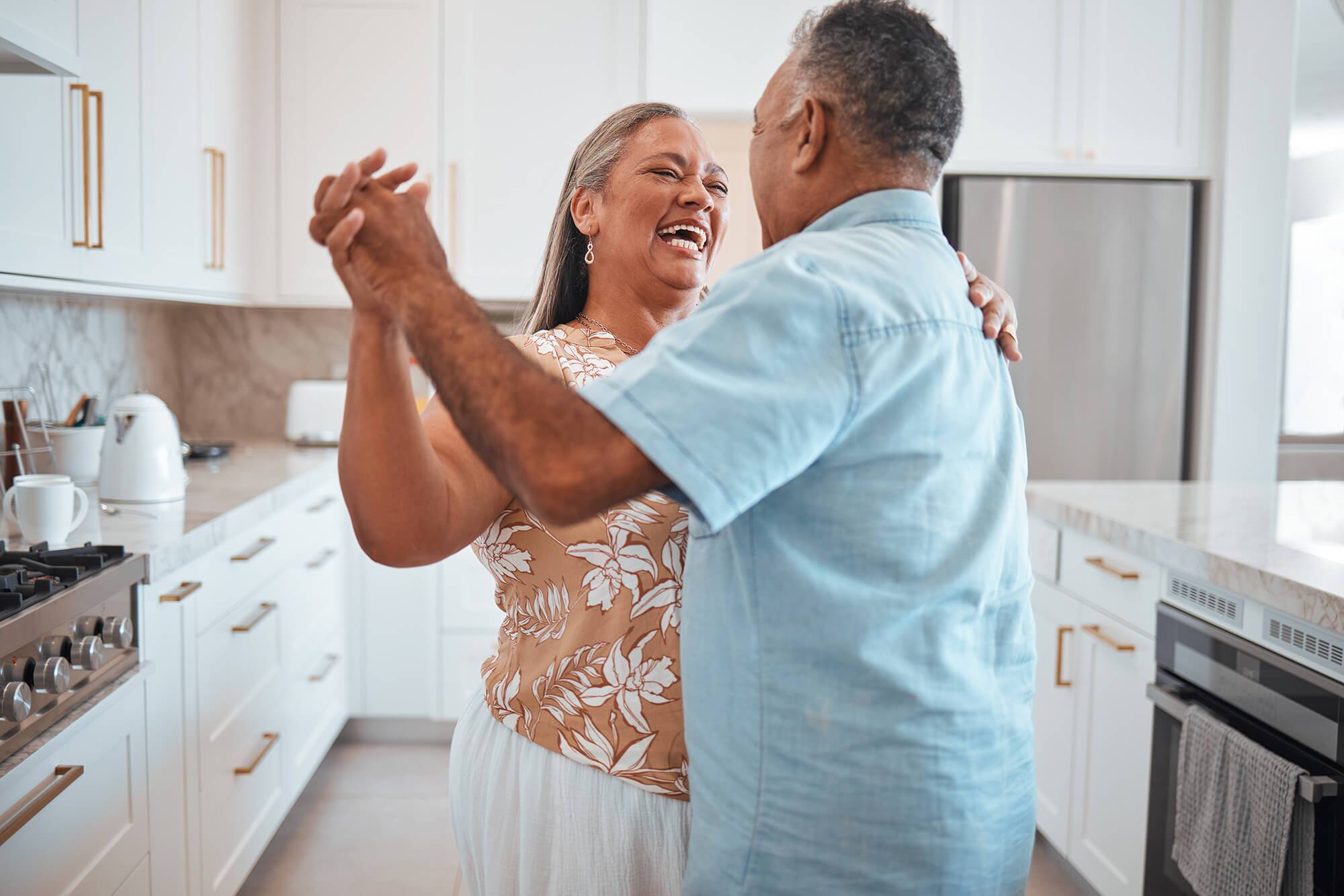 Happy older couple dancing in the kitchen.