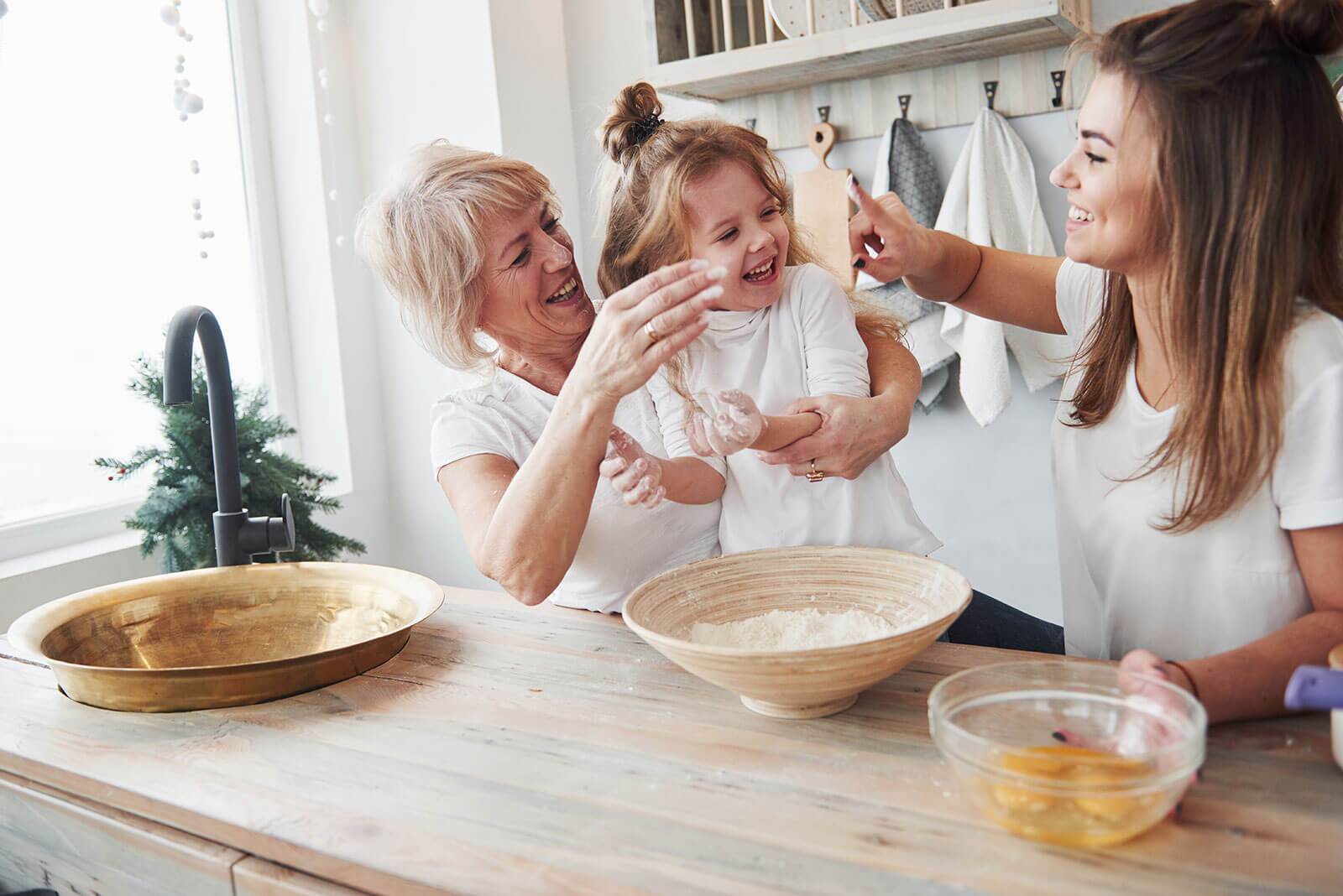 Young daughter and her grandmother having a flour fight with mom in the kitchen.